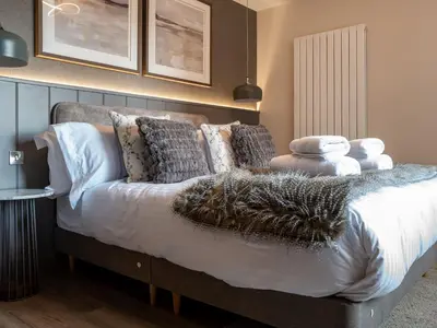 a bedroom with a bed with white sheets and pillows at Arran Shores Luxury Shorefront Garden Terrace Apartment 7 in Lamlash
