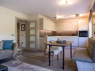 a kitchen and living room with a table and a couch at Arran Shores Luxury Shorefront Garden Terrace Apartment 7 in Lamlash