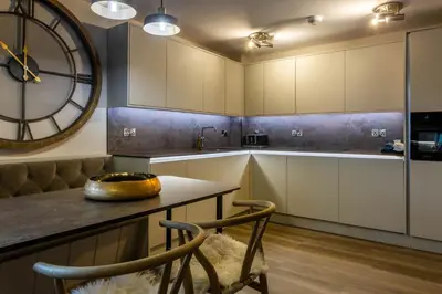 a kitchen with white cabinets and a large clock on the wall at Arran Shores Luxury Shorefront Apartment 9 in Lamlash