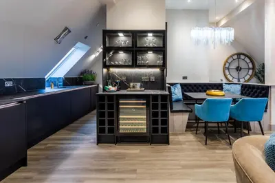 a kitchen and dining room with a table and blue chairs at Arran Shores Luxury Shorefront Penthouse Suite 10 in Lamlash