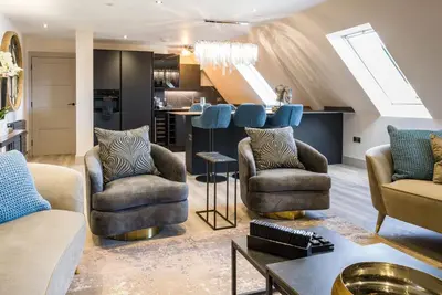 a living room with two chairs and a kitchen at Arran Shores Luxury Shorefront Penthouse Suite 13 in Lamlash