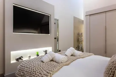 a bedroom with a large bed with a flat screen tv on the wall at Arran Shores Luxury Shorefront Penthouse Suite 13 in Lamlash