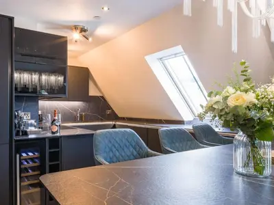 a kitchen with a counter with chairs and a vase of flowers at Arran Shores Luxury Shorefront Penthouse Suite 13 in Lamlash