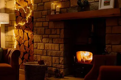 a living room with a brick fireplace with a fire place at Brenachoile Cottage in Callander