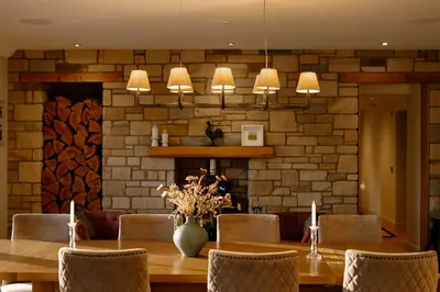 a dining room with a table and chairs and a brick wall at Brenachoile Cottage in Callander