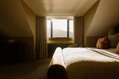 a bedroom with a large bed and a window at Brenachoile Cottage in Callander