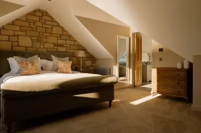 a bedroom with a bed and a brick wall at Brenachoile Cottage in Callander