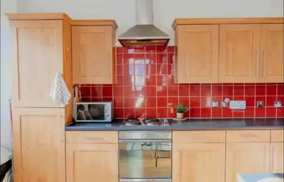 a kitchen with wooden cabinets and red tiles at Glasgow City Centre Apartment in Glasgow