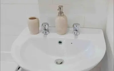 a white bathroom sink with two soap dispensers on it at Glasgow City 1 Bedroom Apartment in Glasgow