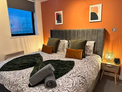 a bedroom with a large bed with orange walls at Stylish 2 bed City Retreat in Glasgow