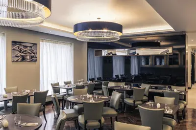 a dining room with tables and chairs and chandeliers at Mercure Edinburgh Haymarket in Edinburgh