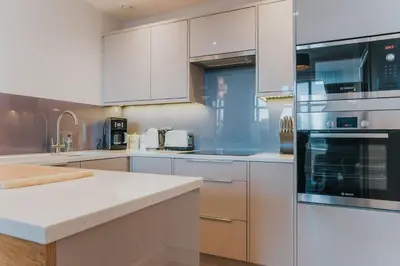 a large kitchen with white cabinets and appliances at Scottish Apartment with Amazing Castle Views in Edinburgh