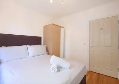 a bedroom with a large white bed with a wooden headboard at Grassmarket Apartment with Amazing Castle View in Edinburgh
