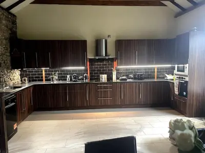 a large kitchen with wooden cabinets and appliances at WestLaigh Central Scotland with outdoor BBQ Hut, pets welcome in Strathaven