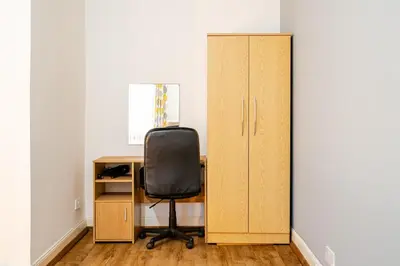 a desk with a chair next to a cabinet at Newly Furnished Flat 4 Minutes Walk To Metro in Glasgow