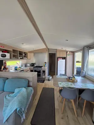 a kitchen and living room with a table and chairs at Barbara's Caravan Craig Tara in Ayr