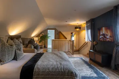 a bedroom with a large bed and a staircase at Luss Cottages at Glenview in Luss
