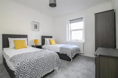 a bedroom with two beds and a window at Tobago Urban Apartment in Greenock