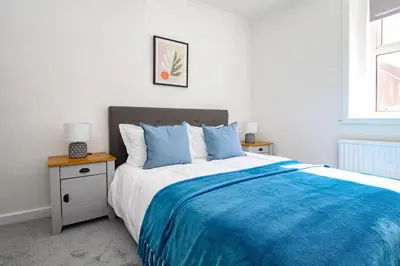 a bedroom with a bed with a blue blanket at Tobago Urban Apartment in Greenock