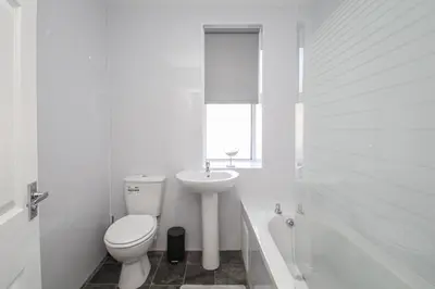 a white bathroom with a toilet and a sink at Tobago Urban Apartment in Greenock