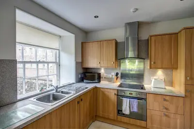 a kitchen with wooden cabinets and a sink and a window at New Lanark Self Catering Waterhouses in Lanark