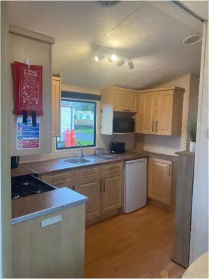 a kitchen with wooden cabinets and a sink and a window at The Wee Sprout in Stranraer
