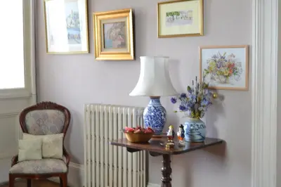 a room with a table with a lamp and a chair at Maybank Guest House in Helensburgh