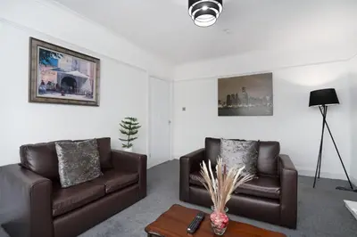 a living room with two brown couches and a table at 2-Bed Flat Wishaw Free Parking Family-Friendly in Wishaw