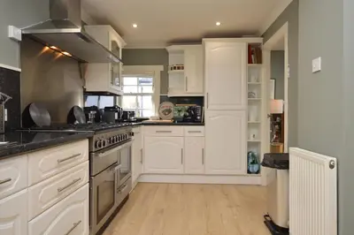 a kitchen with white cabinets and a stove at Old Powdermill Cottage in Tighnabruaich