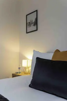 a bedroom with a bed with a black pillow and a lamp at Montgomery Avenue in Paisley