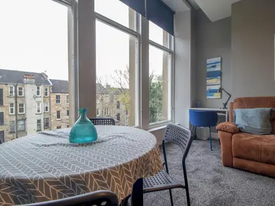 a table with a vase on it in a room with windows at Wonderful West End - Pass the Keys in Glasgow