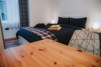 a bedroom with a bed and a wooden table at Large bedroom, close to Airport and City Centre in Edinburgh