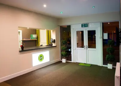a lobby with a door and a sign that says exit at Helix Hotel in Grangemouth