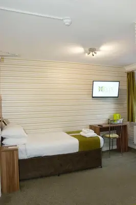 a bedroom with a bed and a tv on the wall at Helix Hotel in Grangemouth
