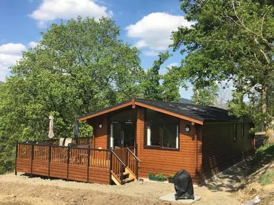 a log cabin with a porch and a deck at Teaghlach Luxury Lodge with hot tub Balquhidder Mhor Lodges in Lochearnhead