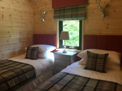 a bedroom with two beds in a log cabin at Teaghlach Luxury Lodge with hot tub Balquhidder Mhor Lodges in Lochearnhead