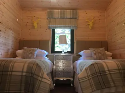 a bedroom with two beds in a log cabin at Teaghlach Luxury Lodge with hot tub Balquhidder Mhor Lodges in Lochearnhead