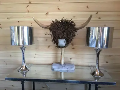 a table with two wine glasses and a cow head with horns at Teaghlach Luxury Lodge with hot tub Balquhidder Mhor Lodges in Lochearnhead