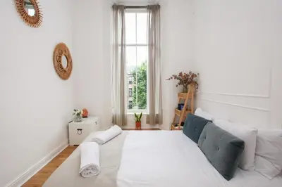 a white living room with a couch and a window at Lovely spacious 2 Bed Flat in Glasgow