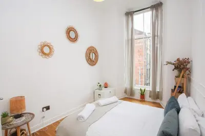 a white bedroom with a large bed and a window at Lovely spacious 2 Bed Flat in Glasgow