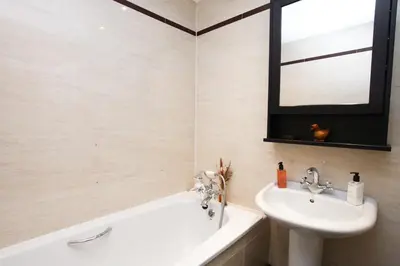 a bathroom with a sink and a tub and a mirror at Lovely spacious 2 Bed Flat in Glasgow
