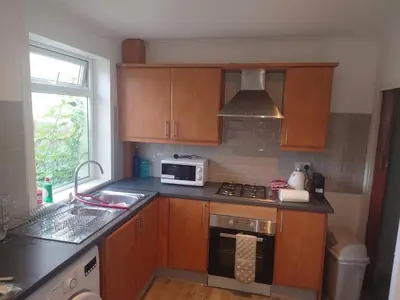 a kitchen with wooden cabinets and a sink and a microwave at 3 bedroom terraced house in Larkhall