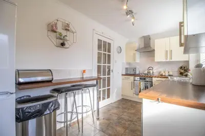 a kitchen with white cabinets and a counter with bar stools at Lena House in Glasgow