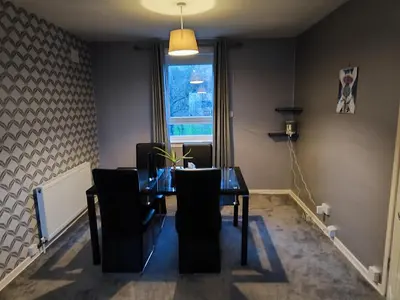 a dining room with a table and chairs and a window at Modern 2-in-1 Retreat for Groups in Port Glasgow
