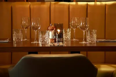 a table with wine glasses and a candle on it at Angels Hotel in Uddingston