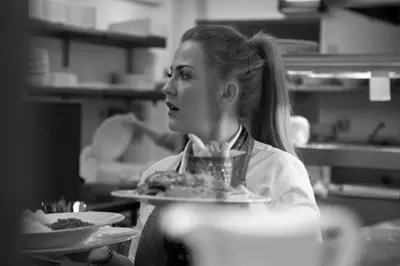 a woman sitting in a kitchen holding a plate of food at Angels Hotel in Uddingston