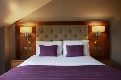 a bed with purple sheets and two purple pillows at Angels Hotel in Uddingston