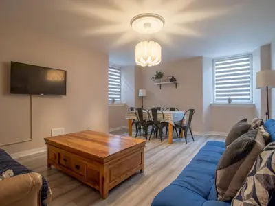 a living room with a blue couch and a table at City Gem Main Door Parking - Pass the Keys in Glasgow