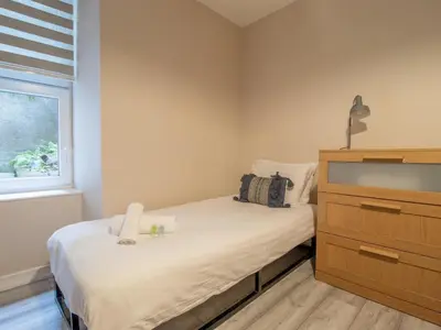 a bedroom with a bed and a dresser and a window at City Gem Main Door Parking - Pass the Keys in Glasgow