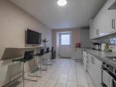 a kitchen with chairs and a counter with a tv at City Gem Main Door Parking - Pass the Keys in Glasgow